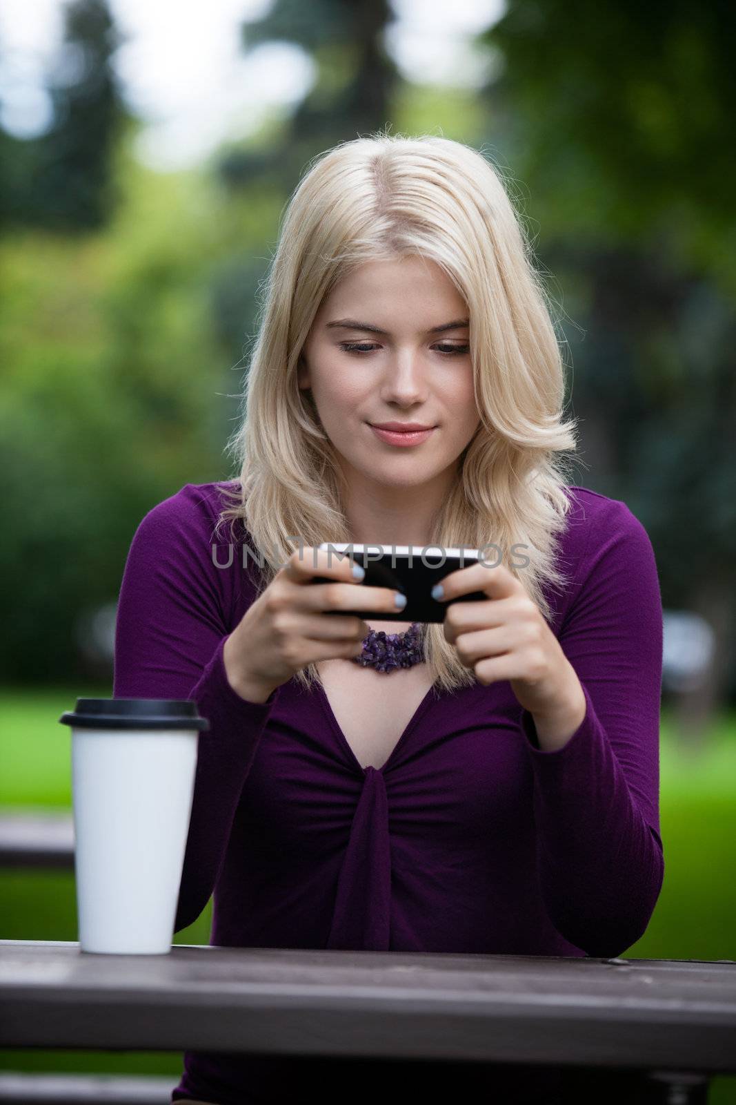Portrait of beautiful college student using cell phone in park