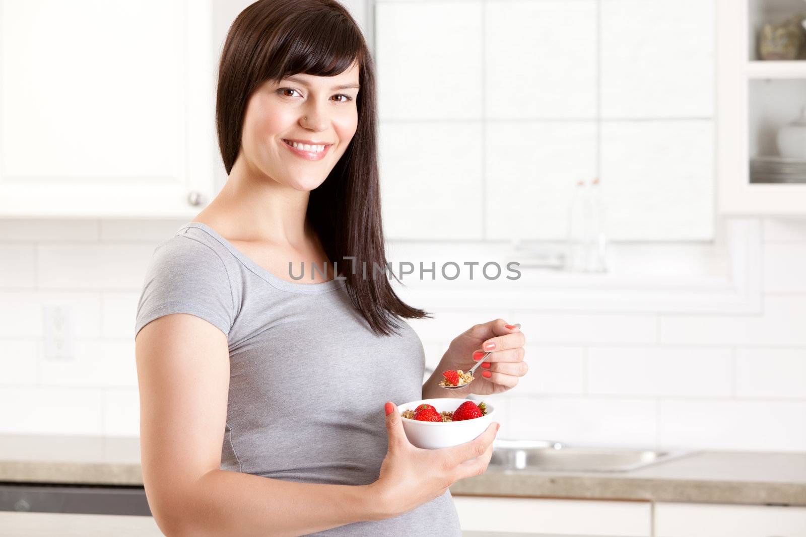 Portrait of a pregnant happy woman eating a healthy meal in kitchen at home