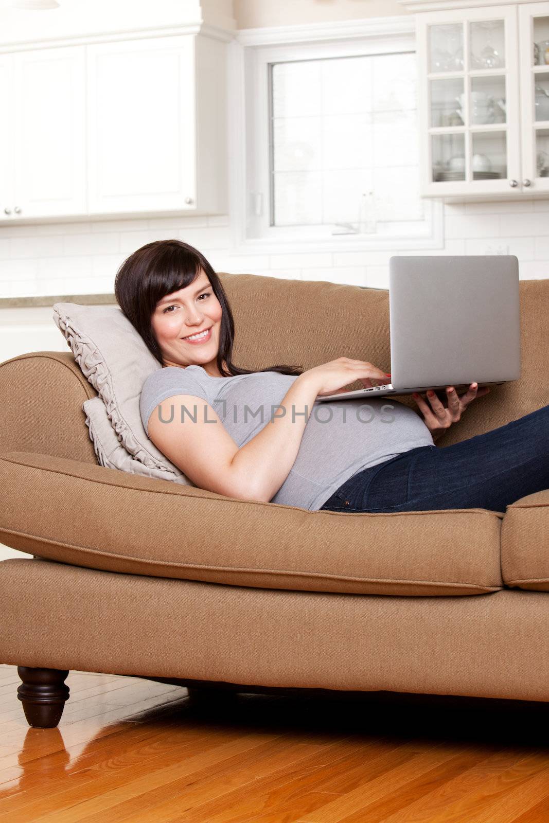 Happy pregnant woman using computer in living room