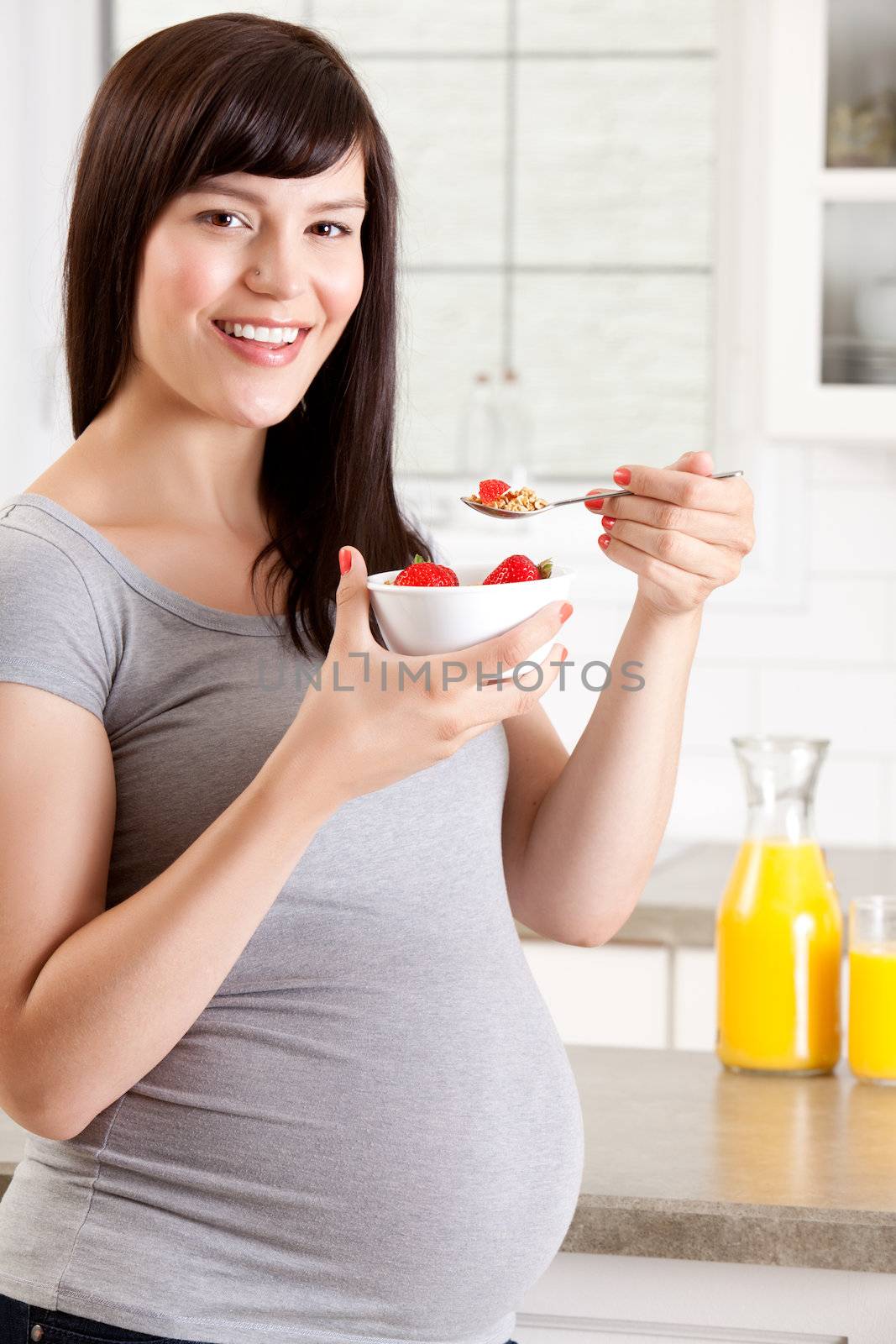 Pregnant woman eating healthy breakfast of granola and strawberries