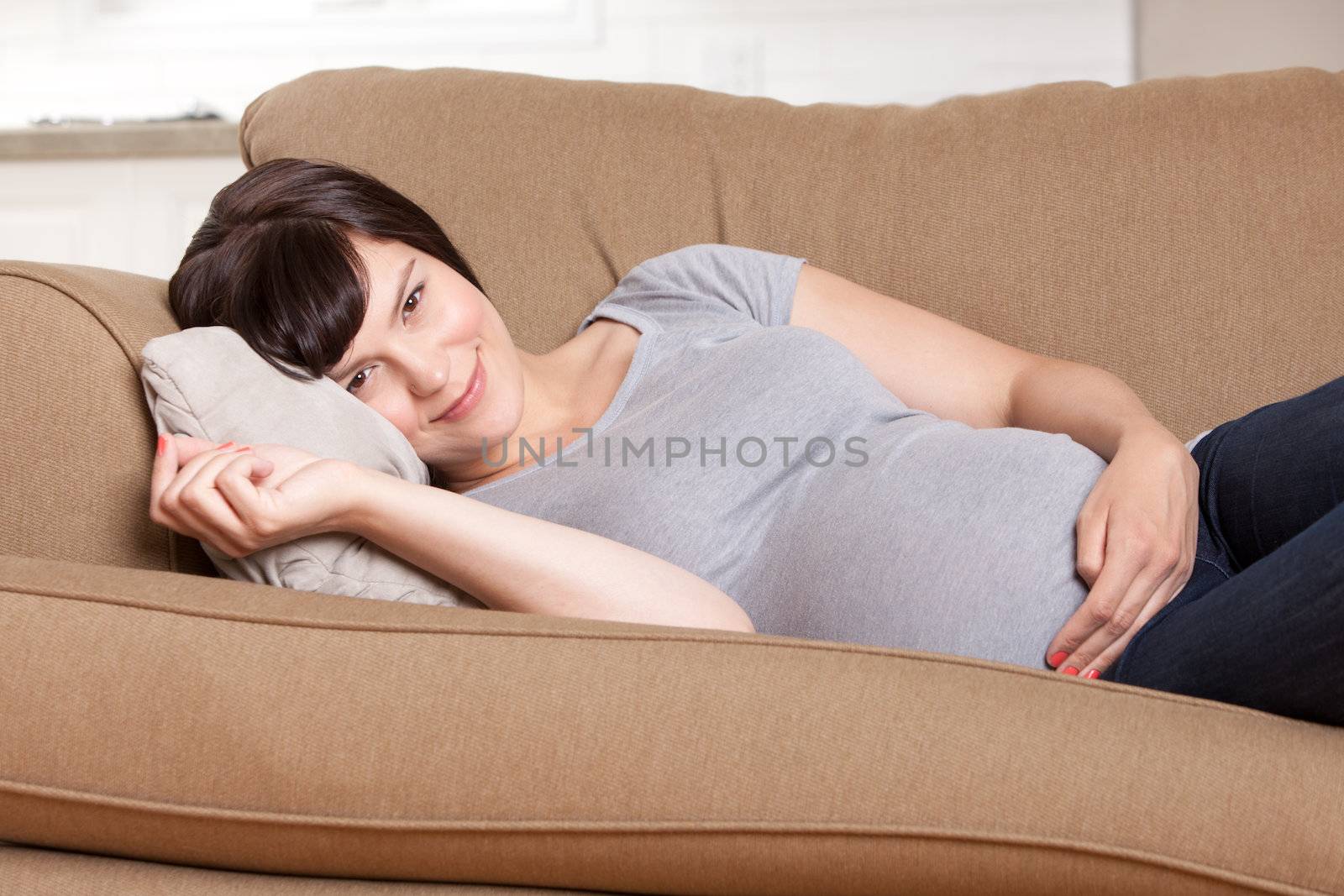 Portrait of a young pretty pregnant woman laying on couch resting