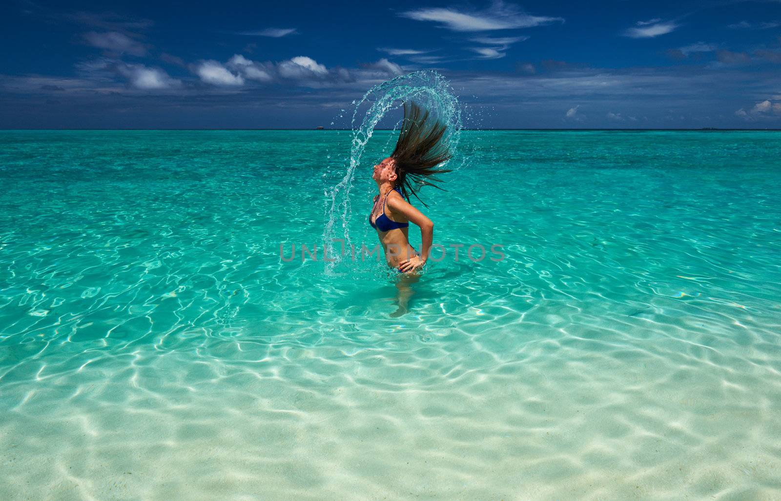 Woman splashing water with her hair in the ocean