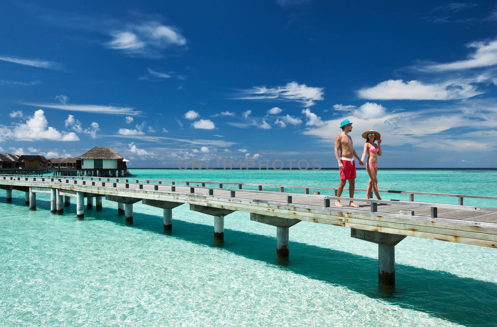 Couple on a tropical beach jetty at Maldives