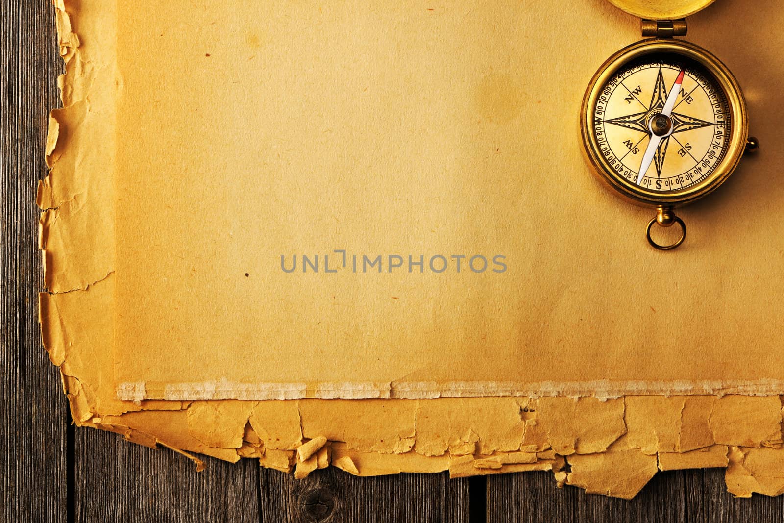 Antique brass compass over old paper background