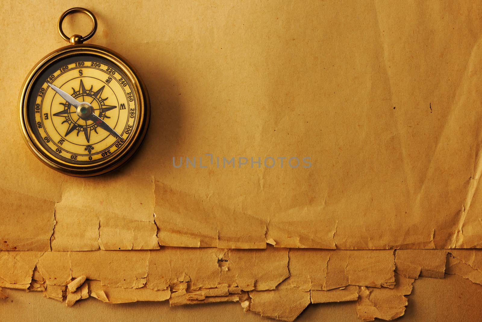 Antique brass compass over old paper background