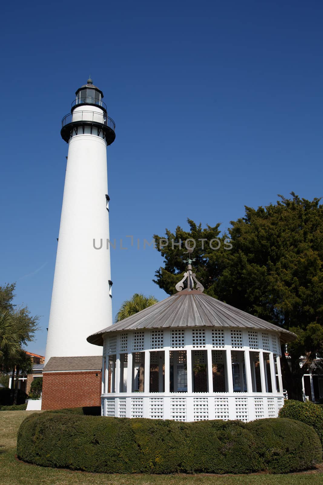 A white lighthouse under clear blue skies with a white gazebo