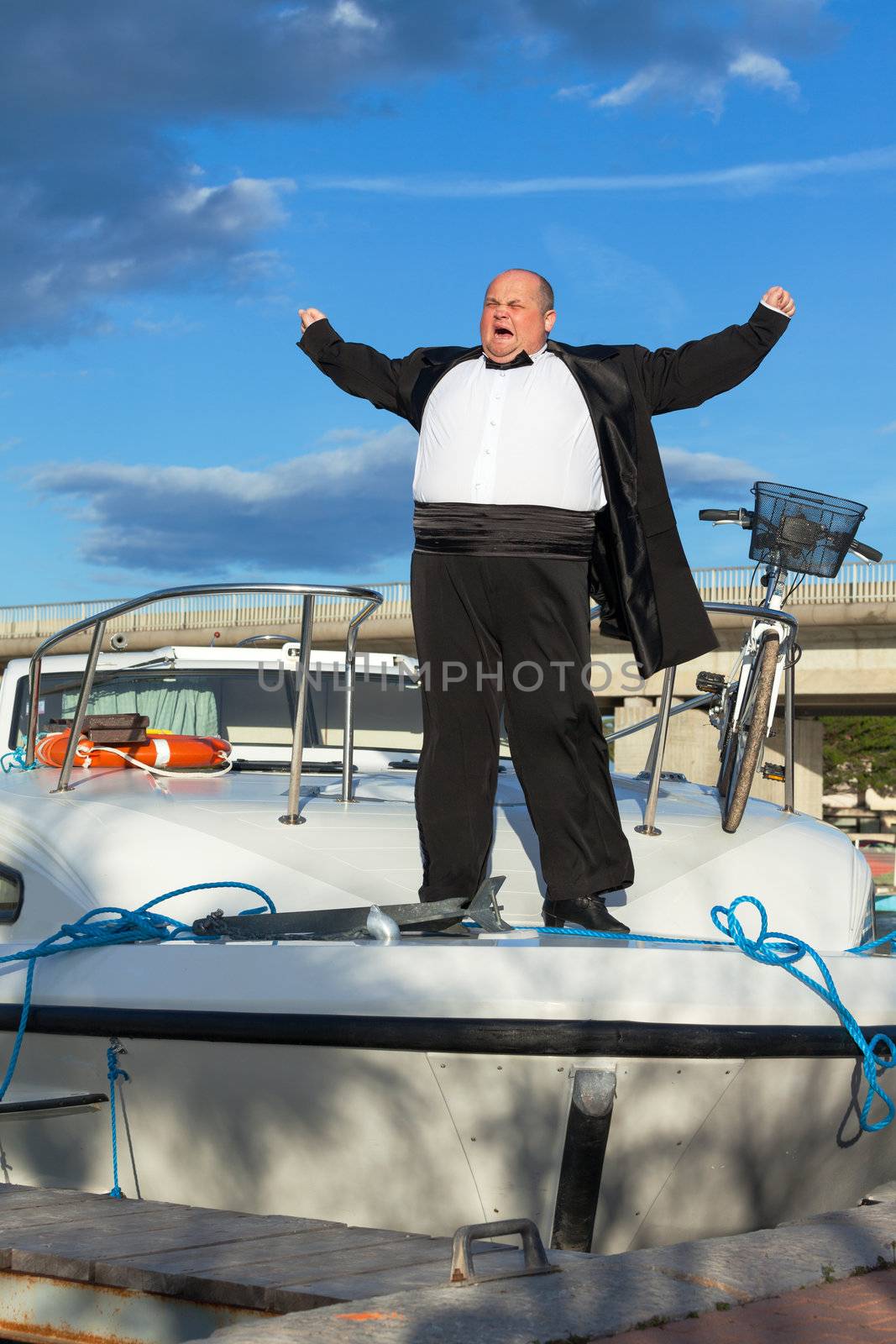 Overweight man in tuxedo standing on the deck of a luxury pleasure boat