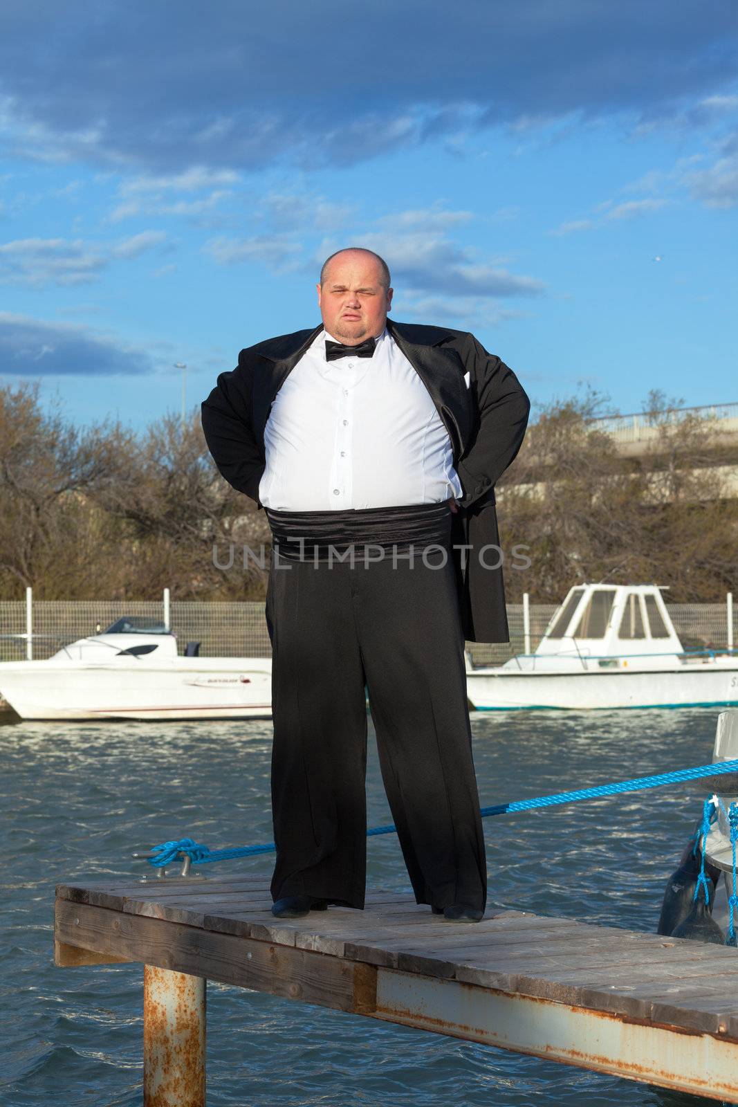 Fat man in tuxedo on pier by Discovod