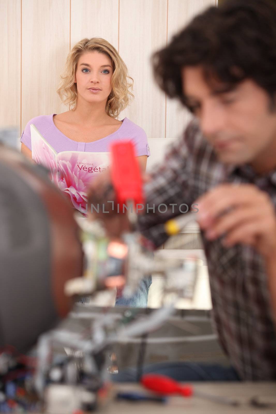 Woman looking at her partner while he fixes an object by phovoir