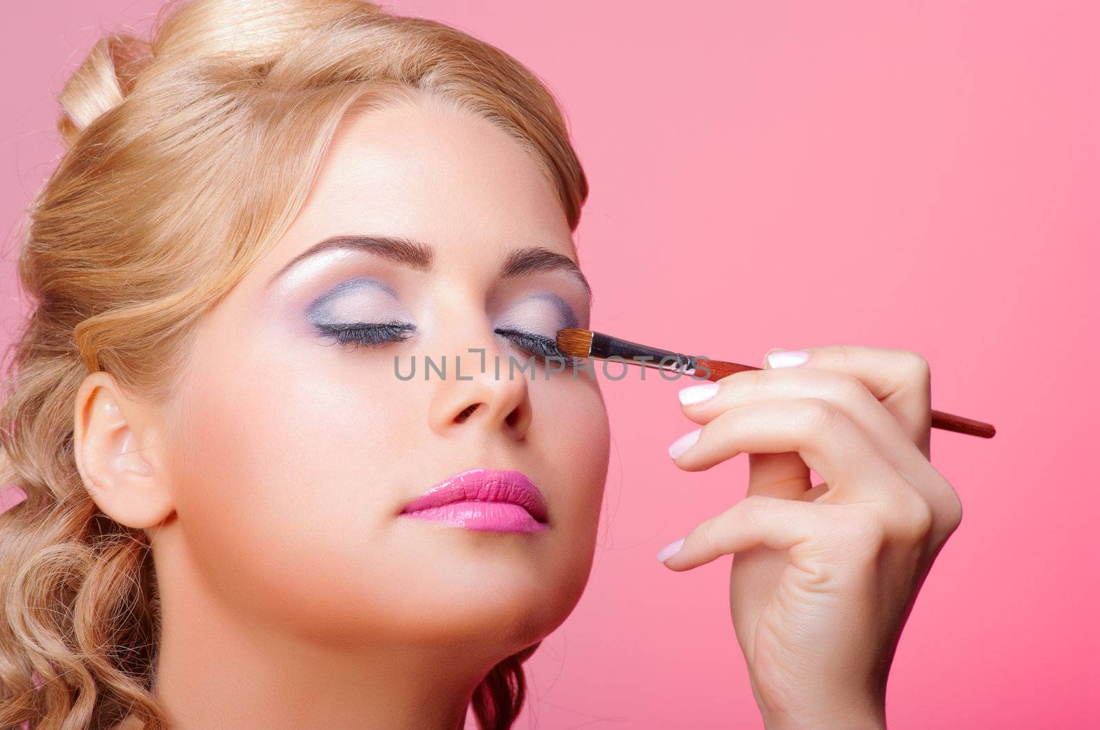Beautiful young woman applying cosmetic paint brush