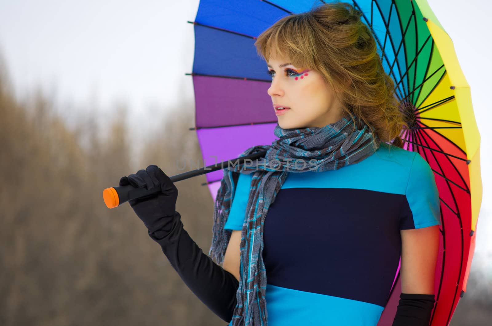 Young woman with multicolor umbrella at winter forest