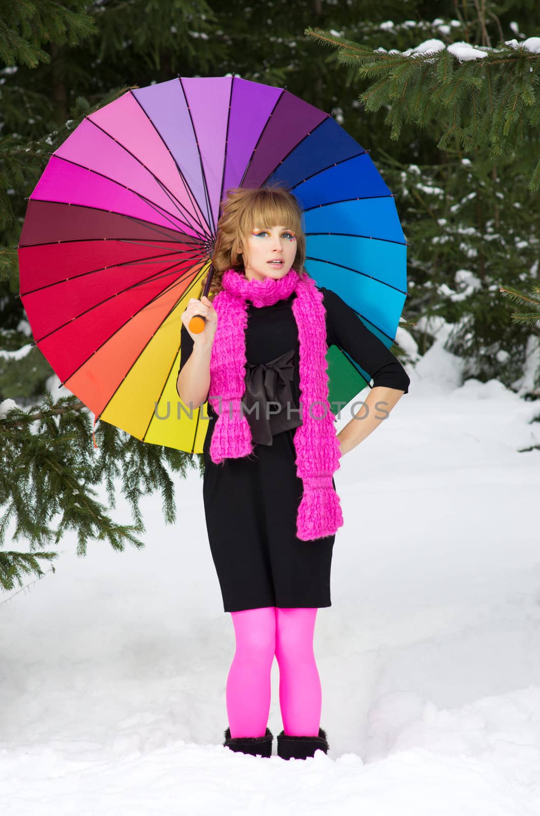 Young woman with multicolor umbrella at winter forest