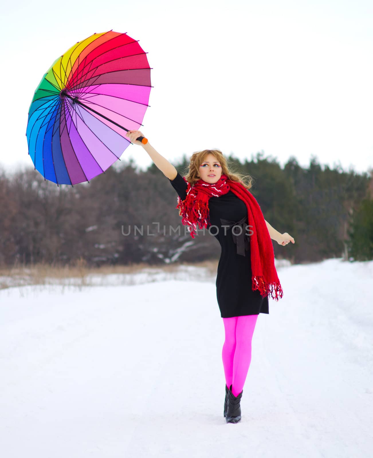 Young woman with multicolor umbrella at winter forest