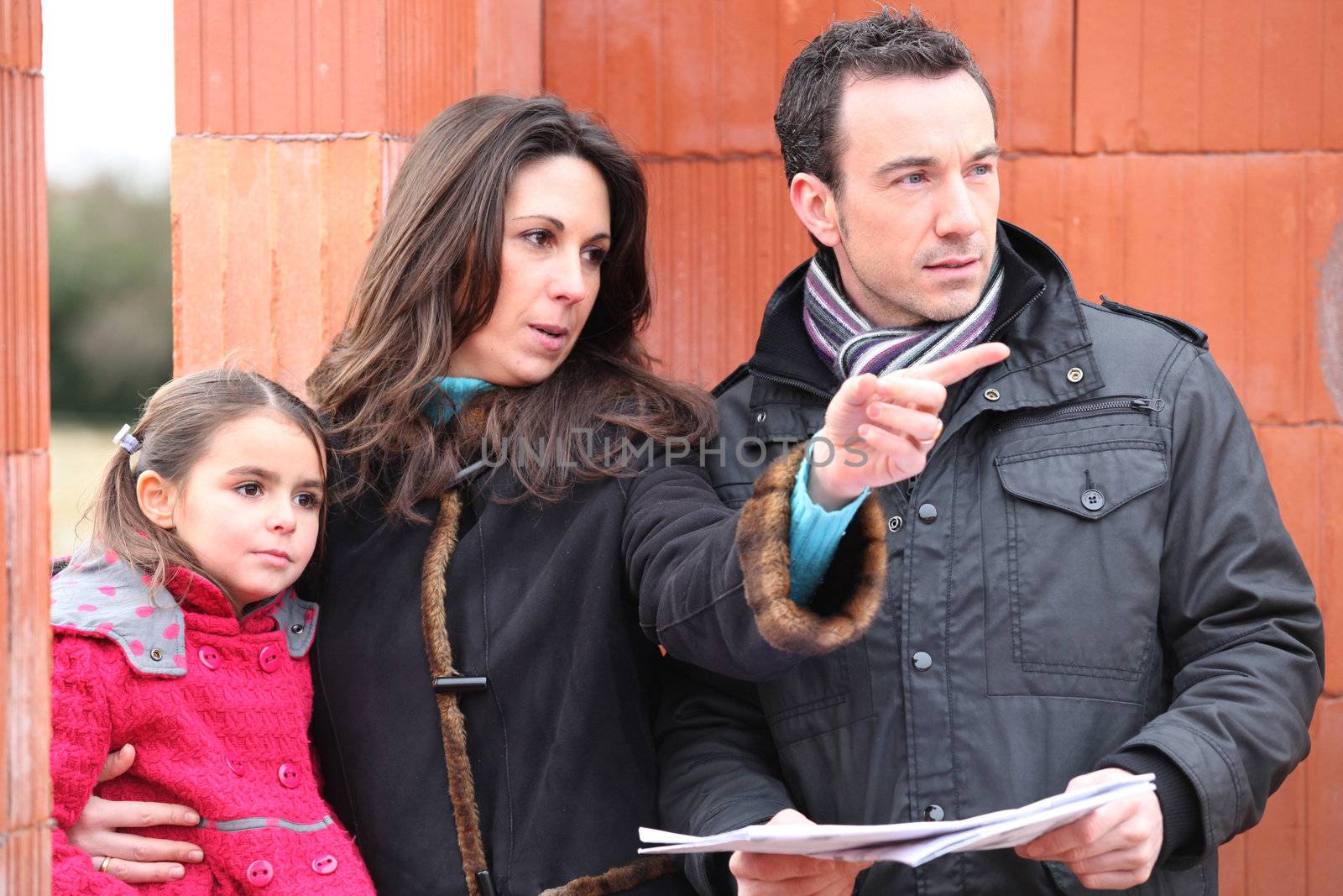 family looking at the plan of their future house by phovoir