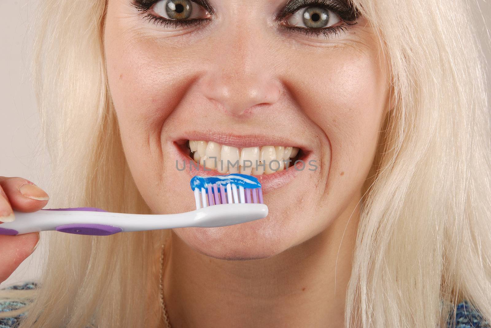 Young blonde woman brushing her teeth