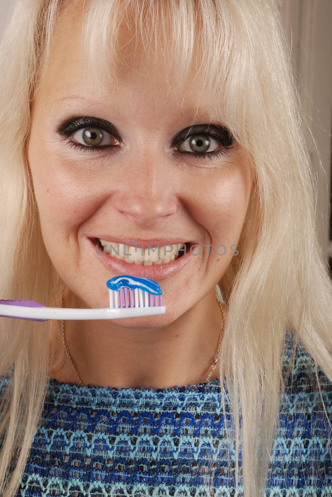 Young blonde woman brushing her teeth