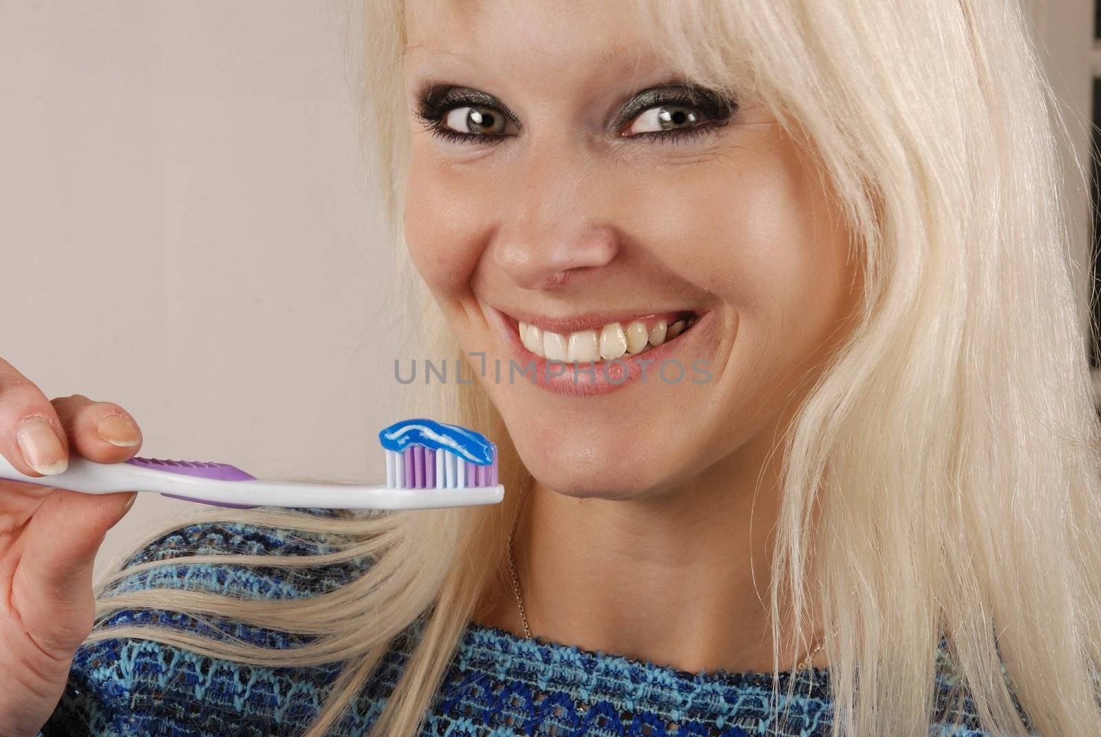 Young blonde woman brushing her teeth