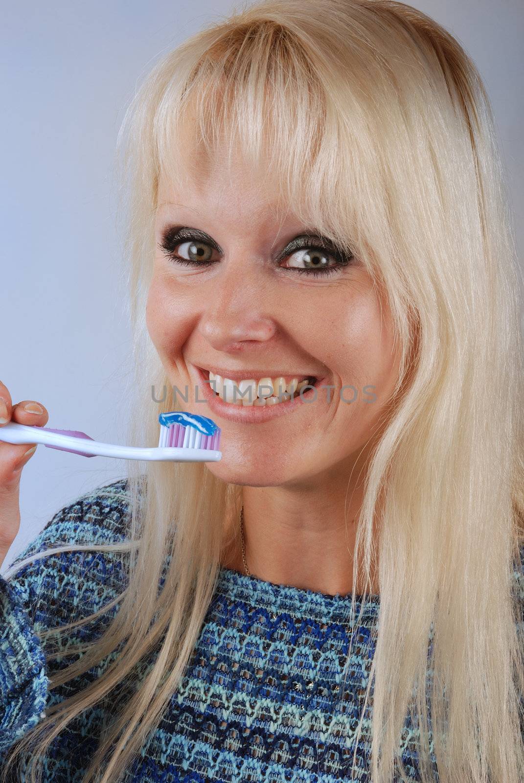 Young blonde woman brushing her teeth