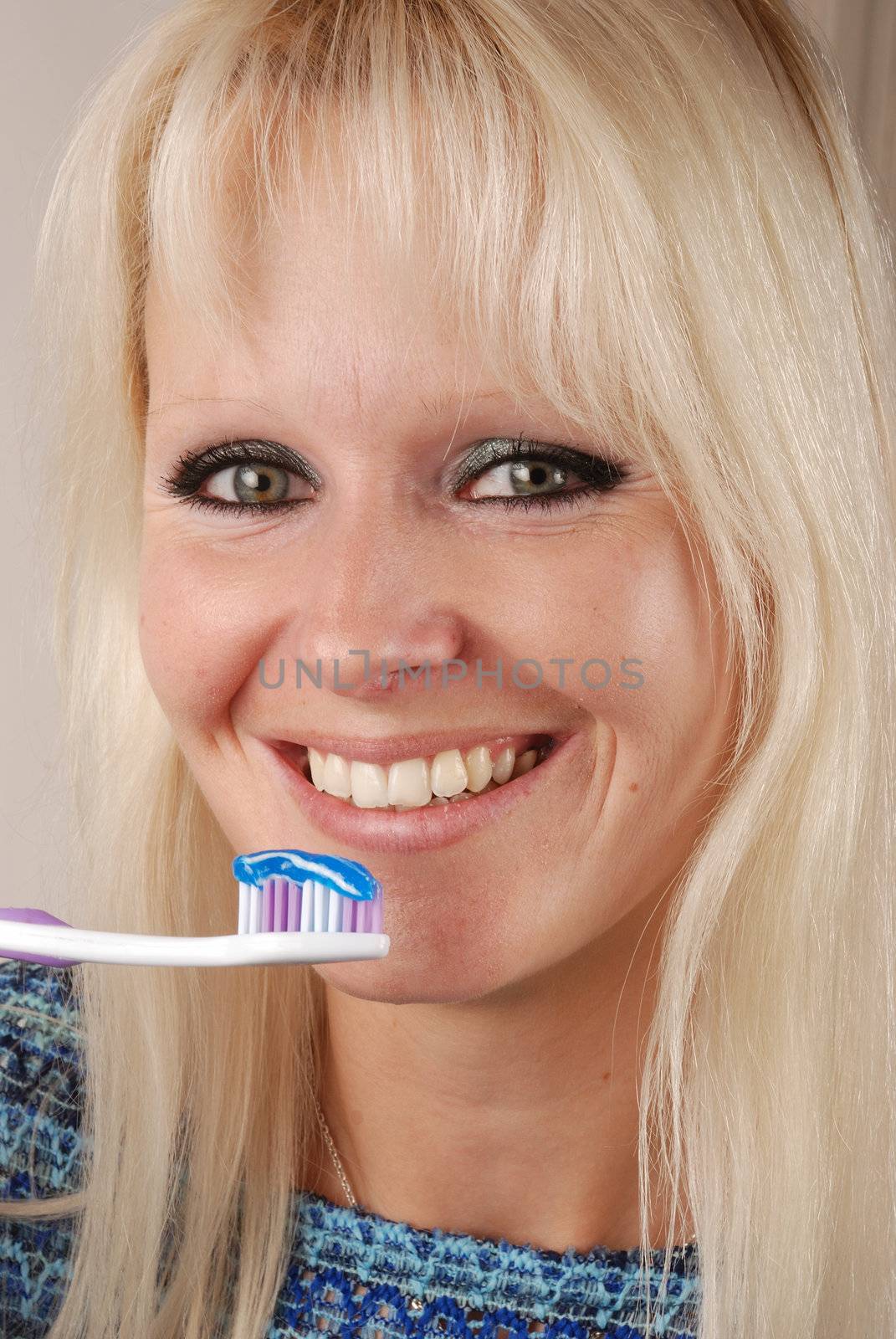 Young blonde woman brushing her teeth