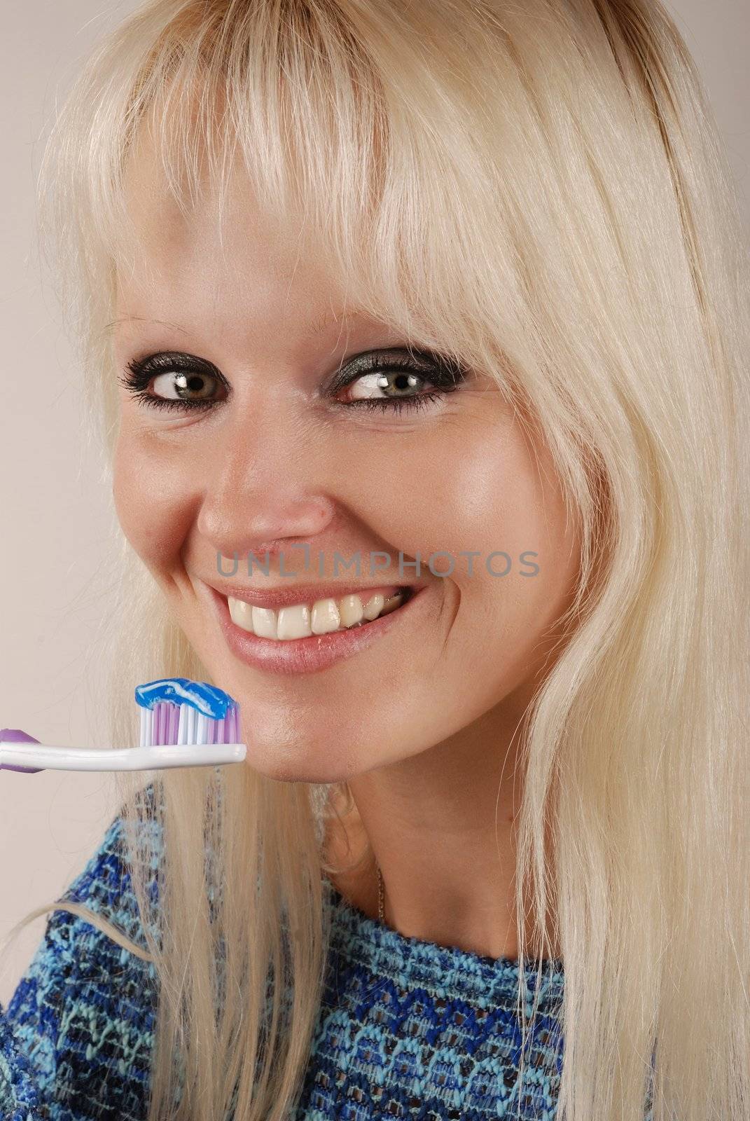 Young blonde woman brushing her teeth