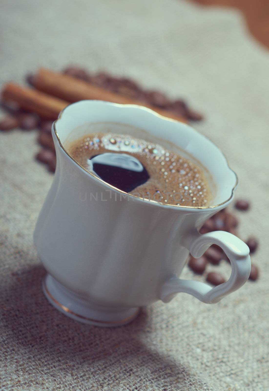 Coffee cup with cinnamon and coffee beans background