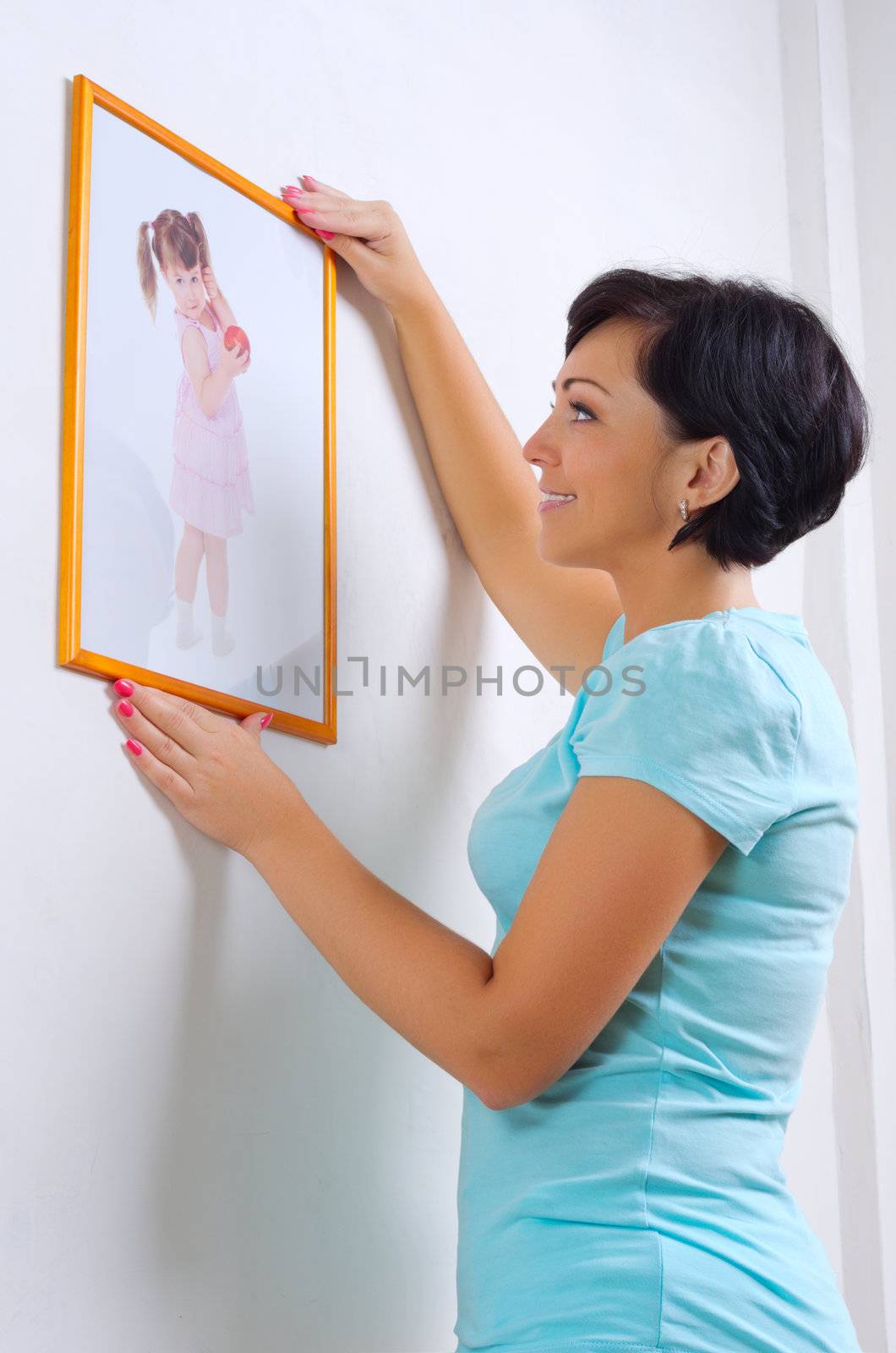 Woman hanging up photo of little girl by rbv