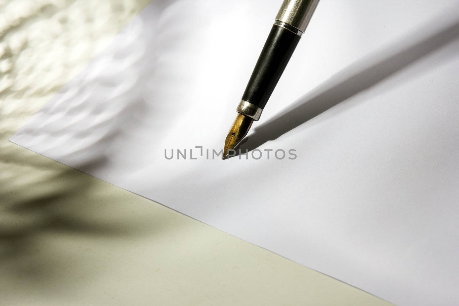 A sheet of white paper and fountain pen with gold nib at the work desk