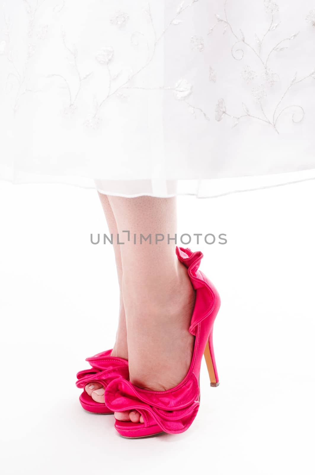 Close up shot of womans feet in hot pink stilettos on an isolated white background.