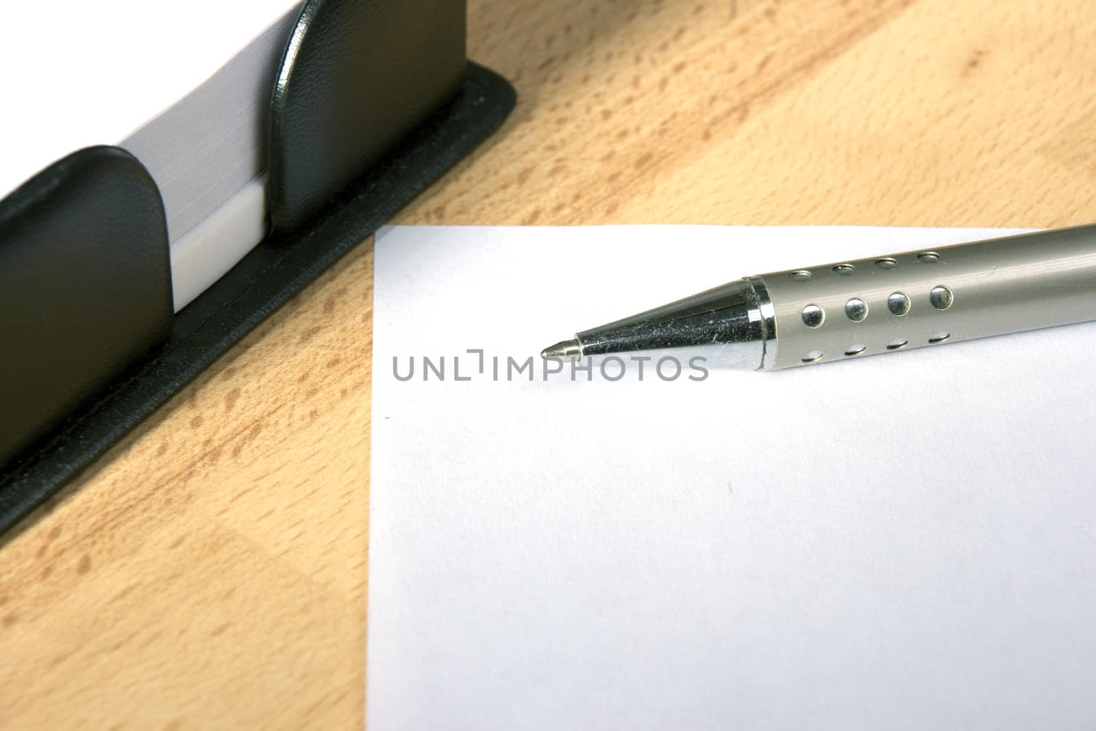 White sheet of paper and a silver pen at work desk