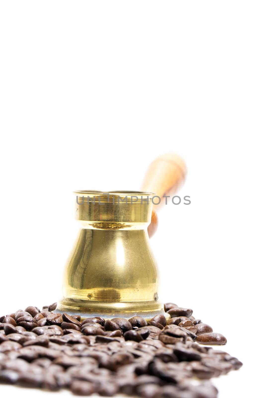 Bronze Turk (Cezve) in the midst of fresh roasted coffee beans on a white background