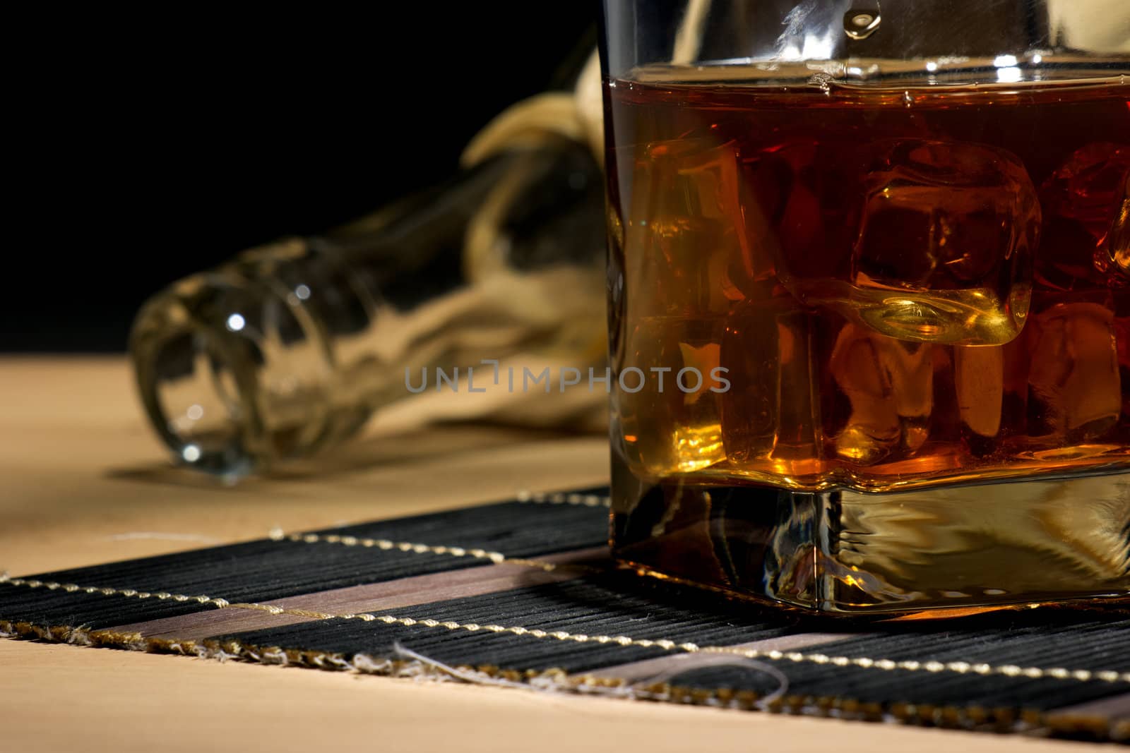 A glass of aged old whiskey on the rocks on black background