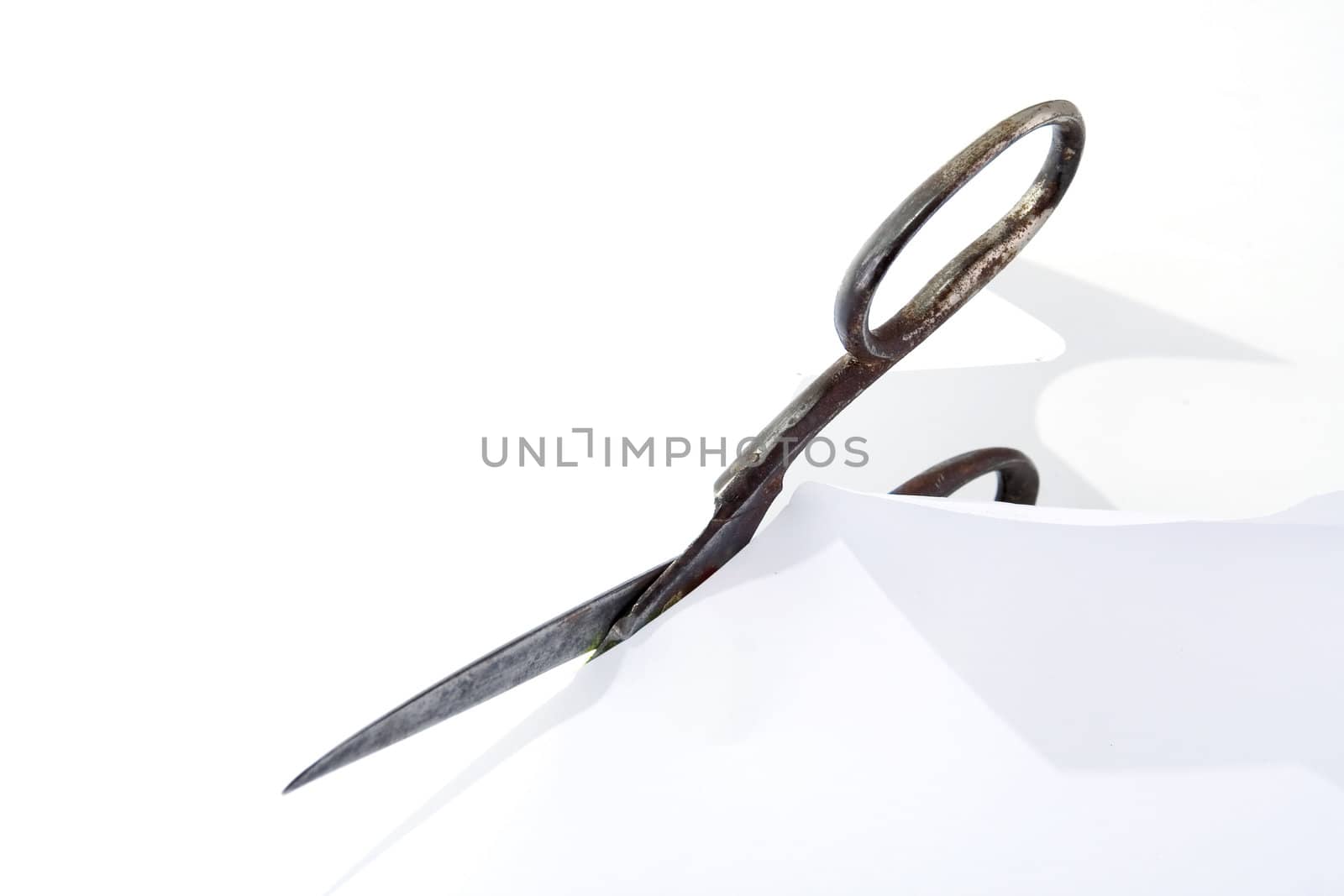 Old rusty steel scissors cut paper on white background