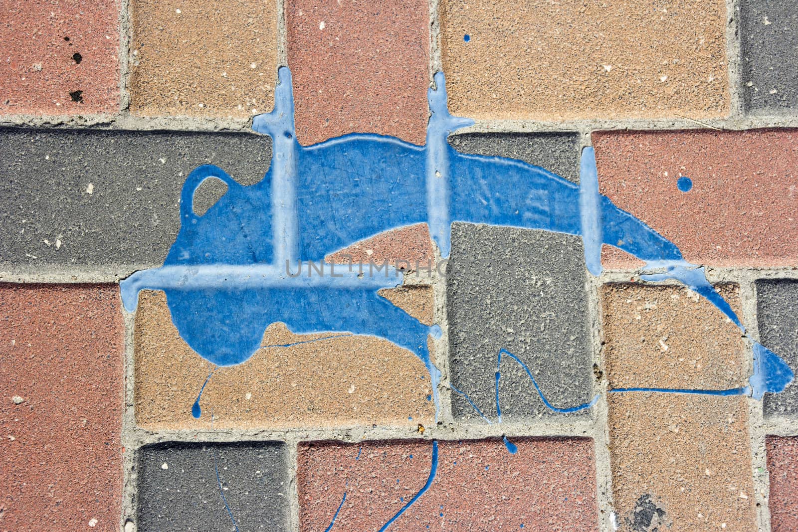 The texture of the pavement, lined red-brown, dark gray and orange brick with a spot of dry bright blue paint. Abstract background for graphic design