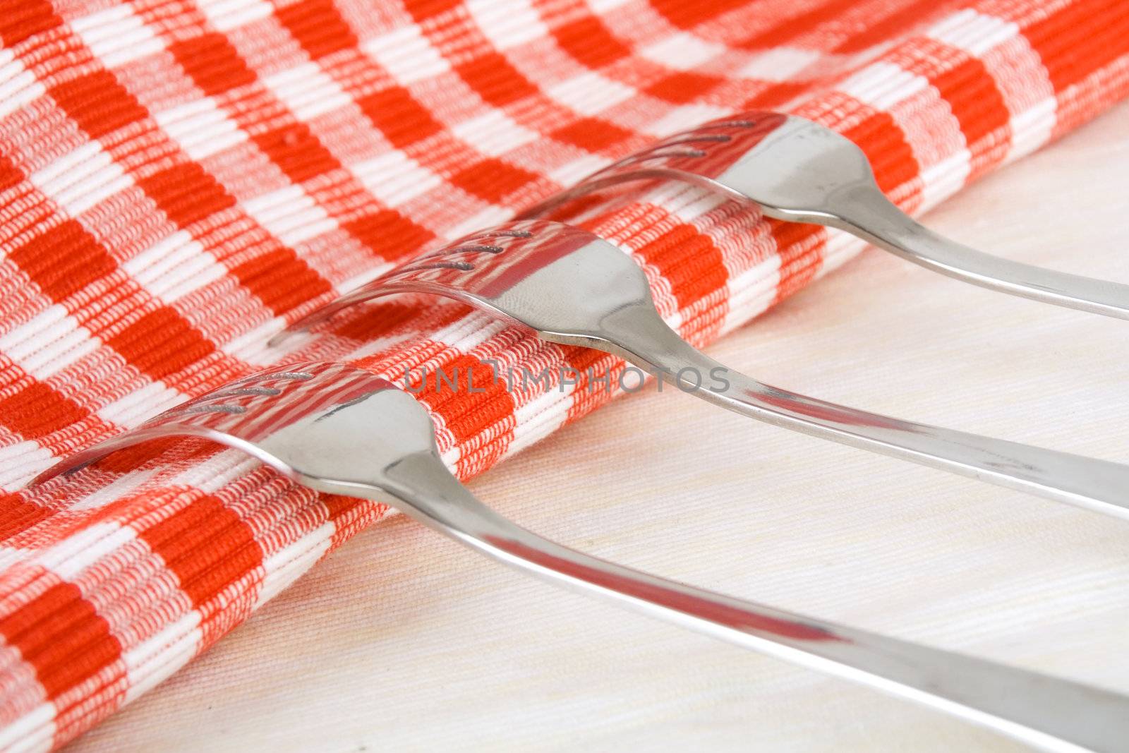 Shiny stainless steel forks on checkered fabric