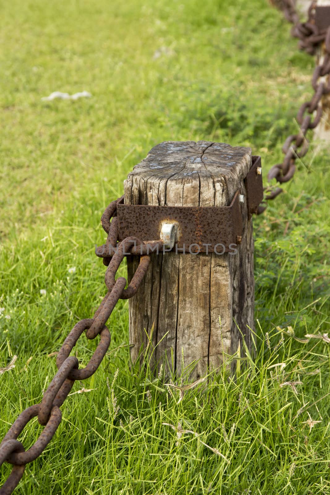 Decorative fence made of cracked wooden beams and rusty iron chain