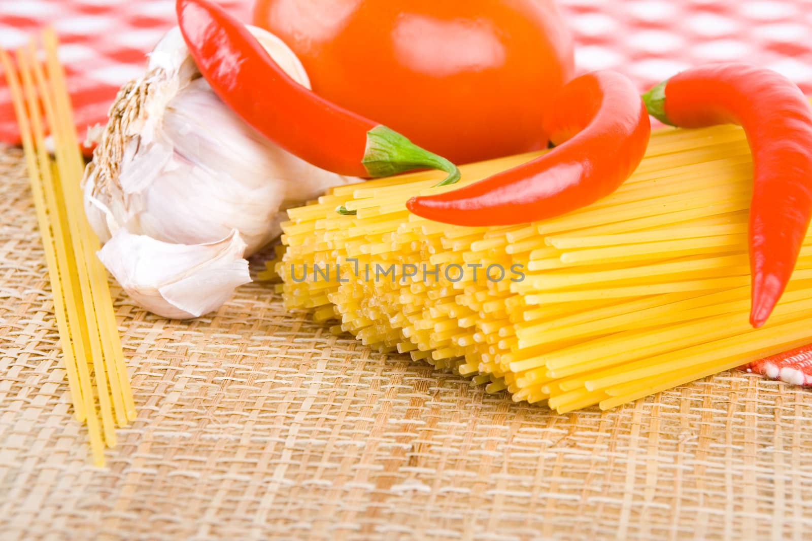 Golden raw dried Italian pasta with other ingredients on kitchen desk.