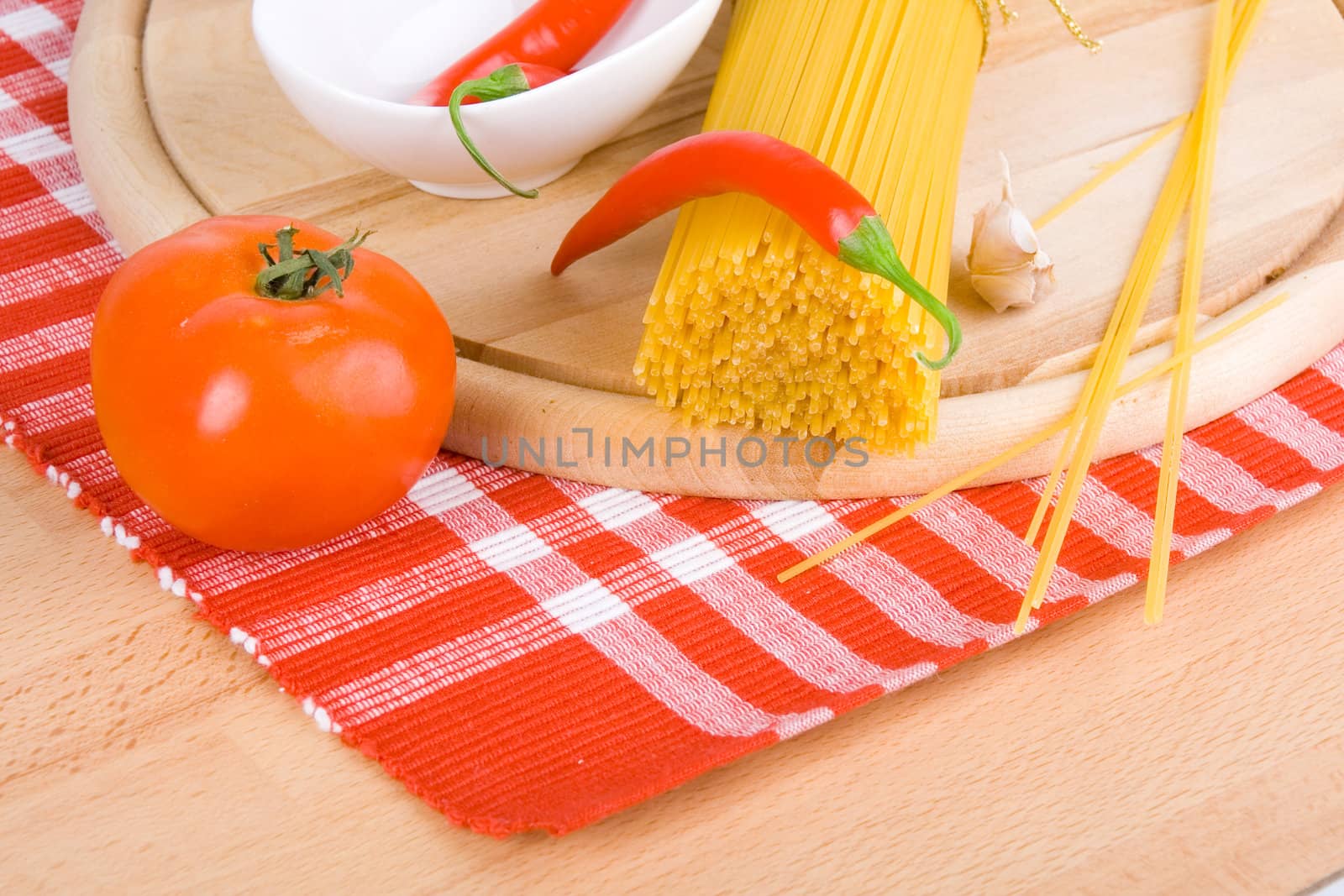 Golden raw dried Italian pasta with other ingredients on kitchen desk.