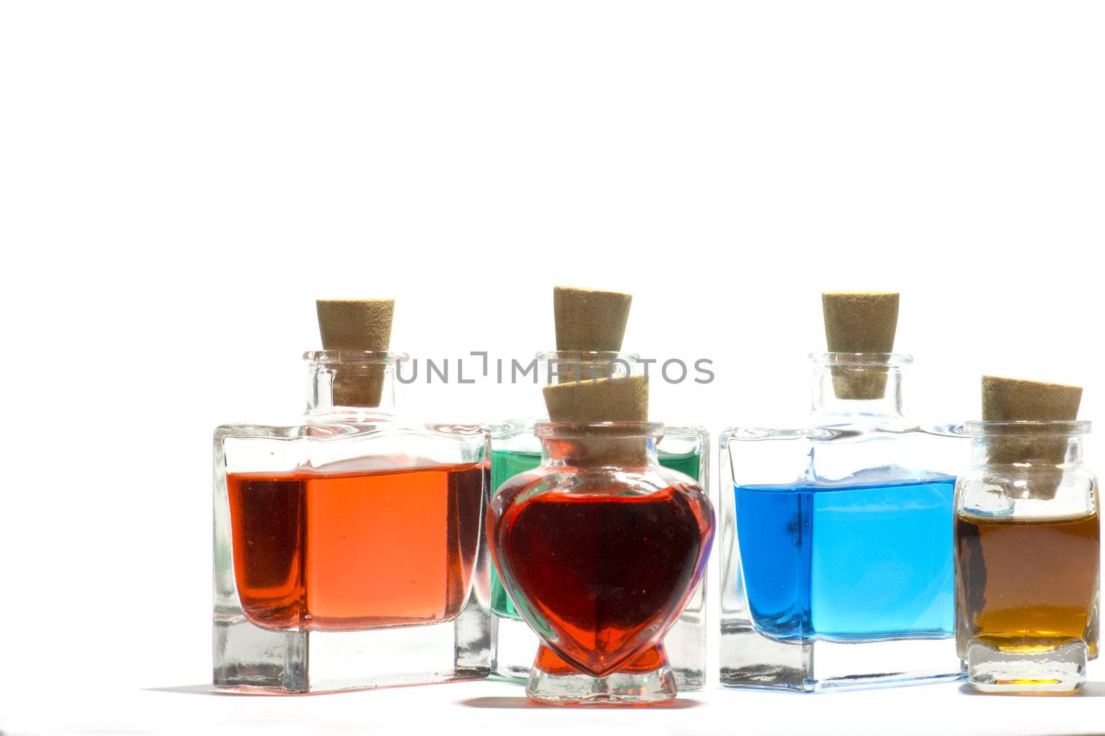 Clear glass vials filled with red, green and blue liquid on a white background