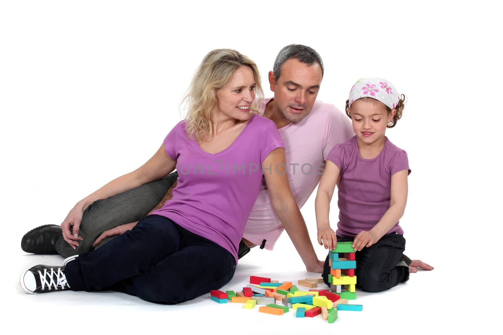 Parents watching their daughter play with blocks by phovoir