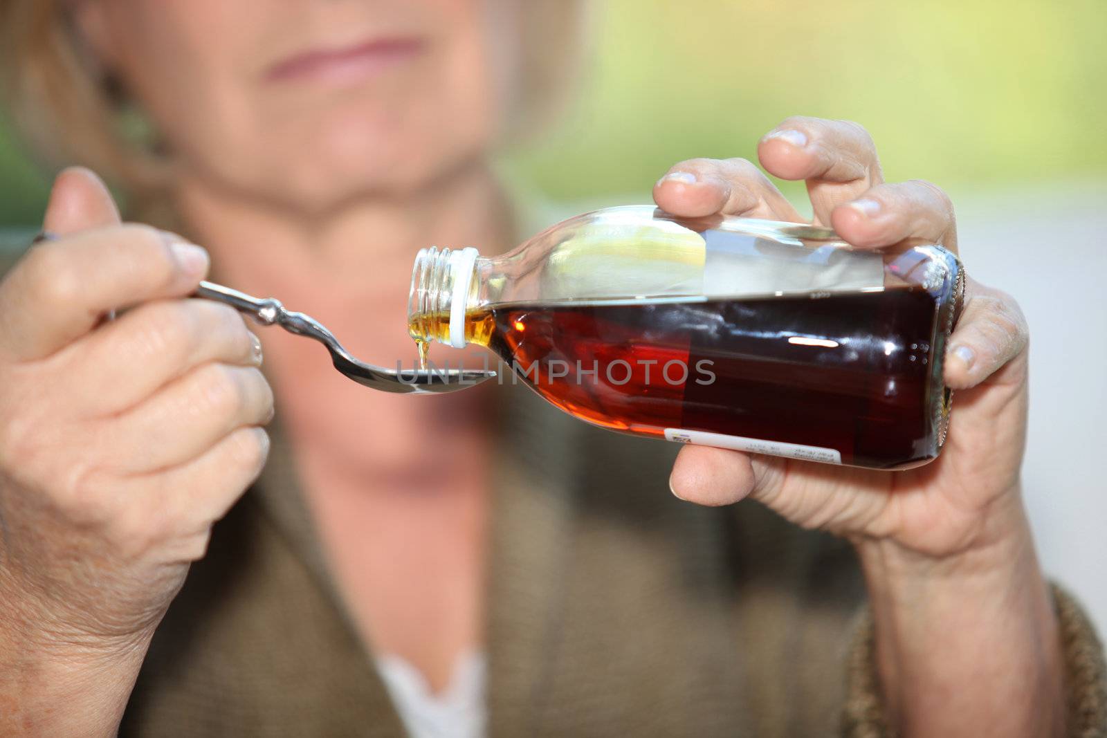 Woman taking cough medicine by phovoir