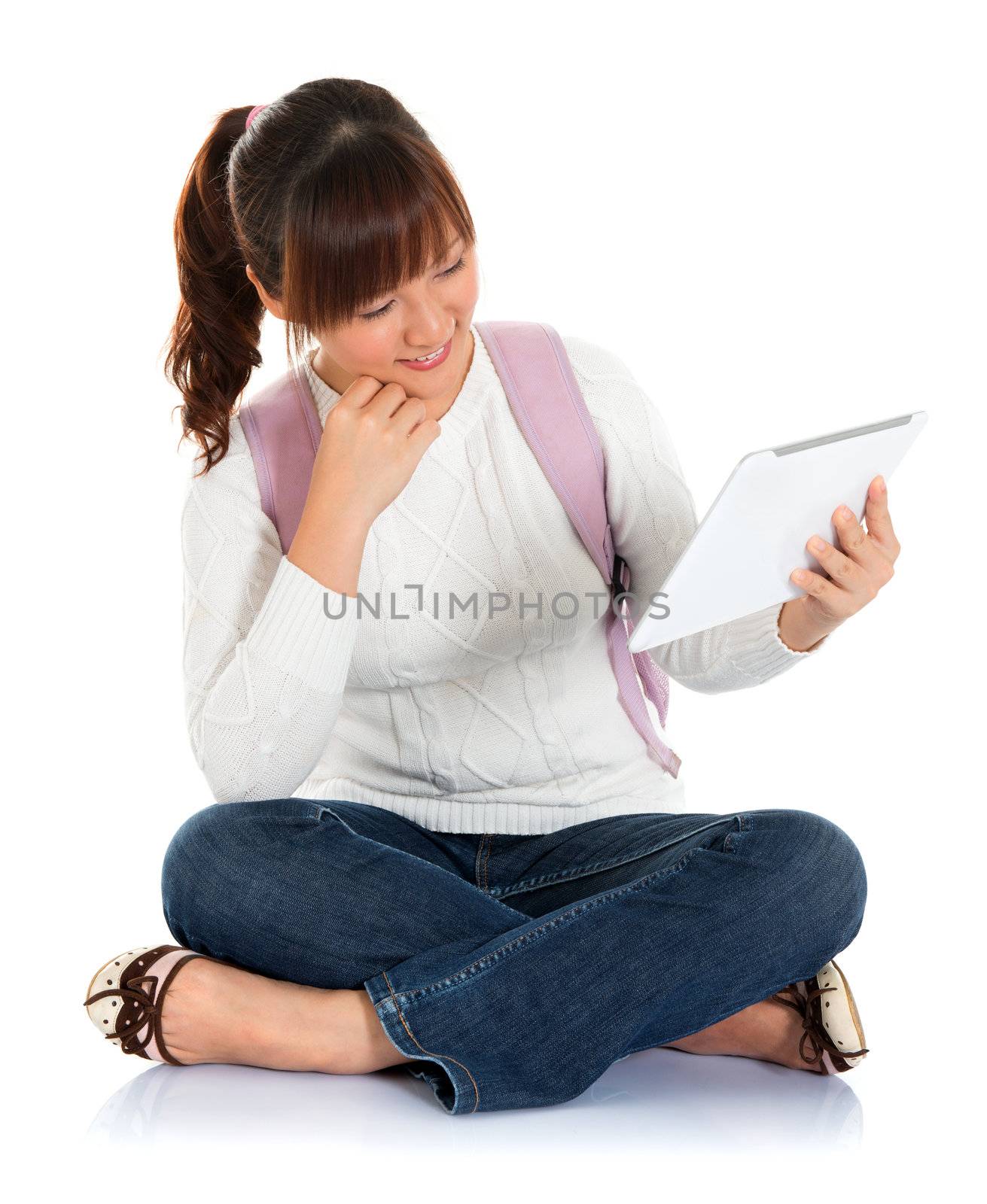 Full body Asian female young adult student sitting on floor using tablet pc isolated on white background