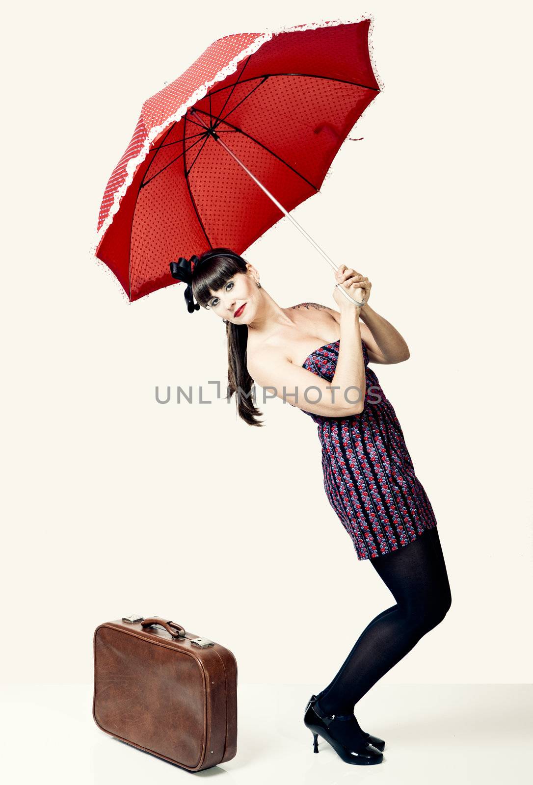 Beautiful woman with a vintage look posing with a red umbrella