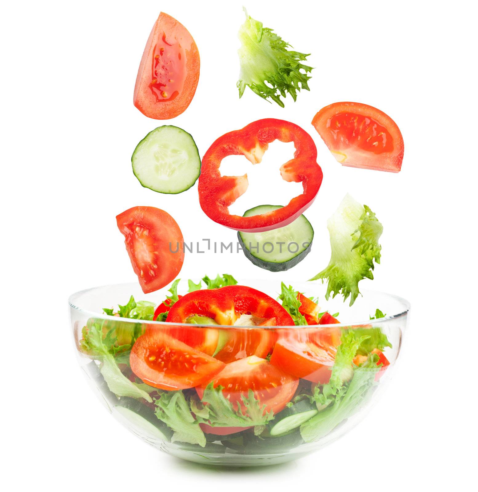 Fresh vegetables falling into the glass bowl isolated over white background