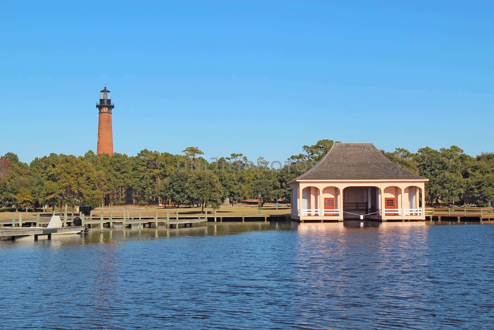 The red brick structure of the Currituck Beach Lighthouse and the pink boathouse at Currituck Heritage Park near Corolla, North Carolina