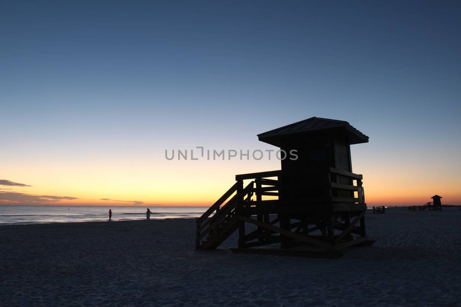 Lifeguard station on Siesta Key Beach, Florida, is silhouetted against the setting sun with a dark blue and orange sky