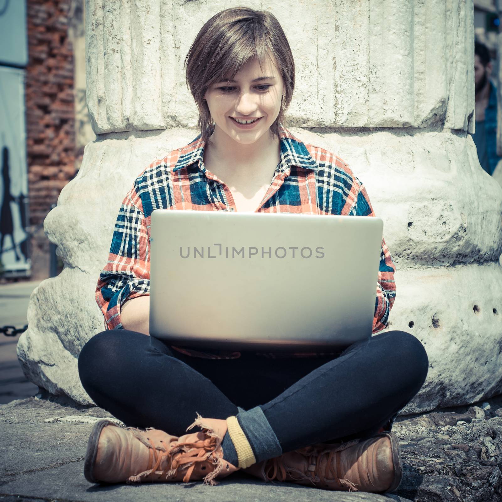 young woman using notebook in the street