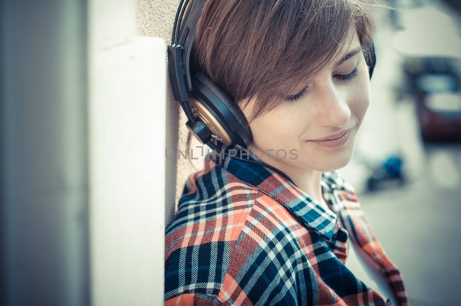 young hipster woman listening to music on balcony
