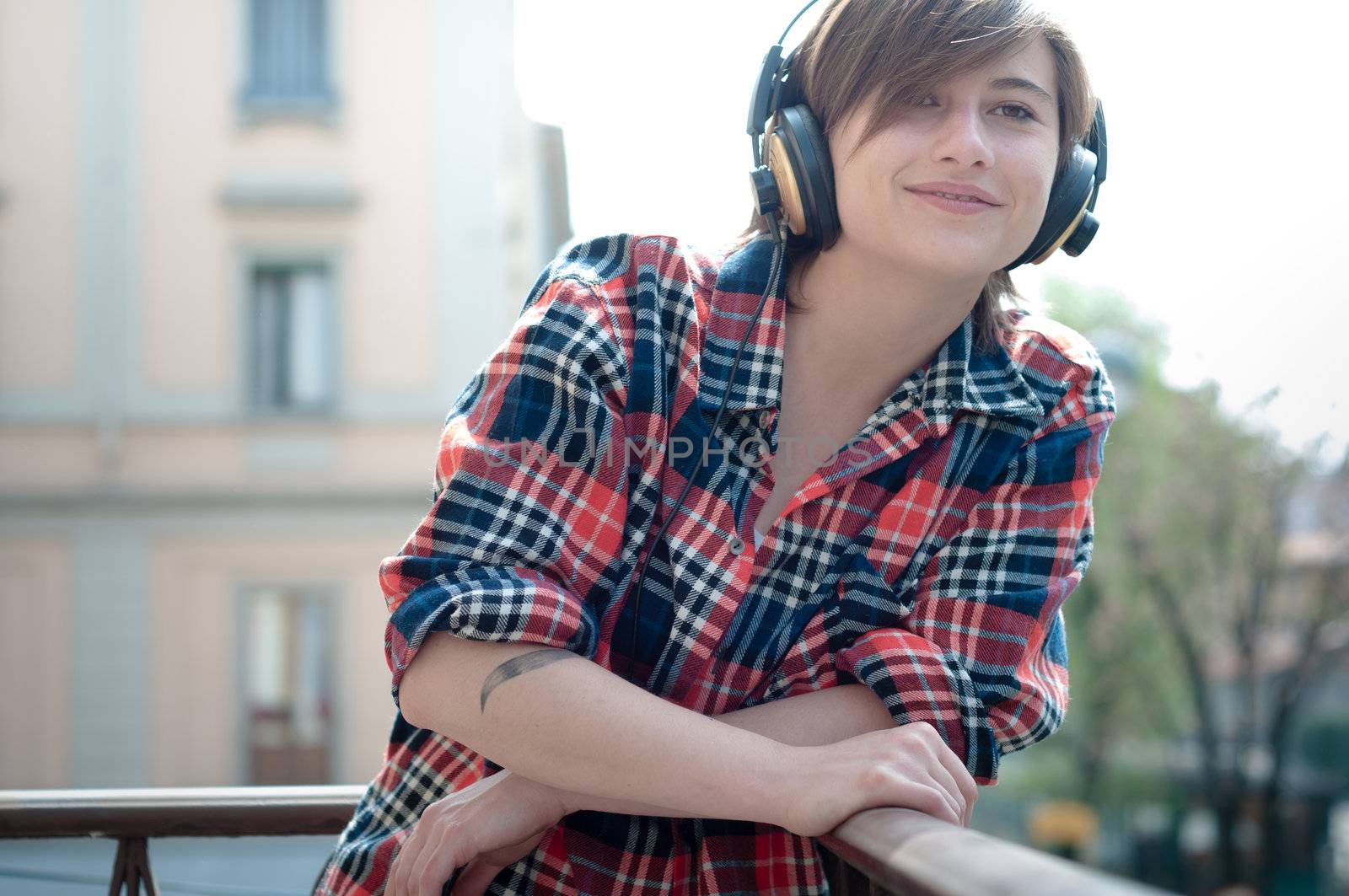young hipster woman listening to music on balcony