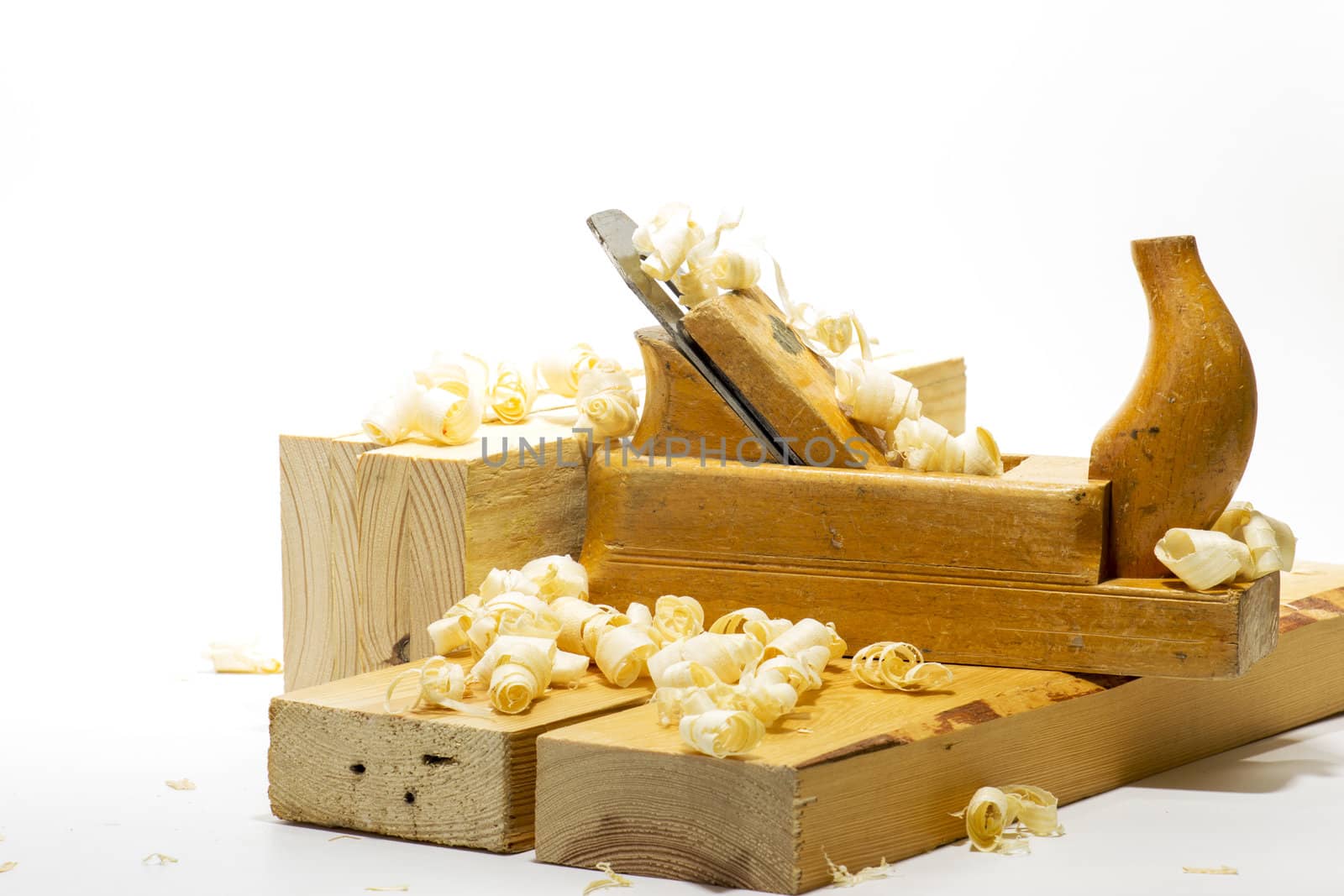 Wooden plane, boards and planed wood shavings on a white background