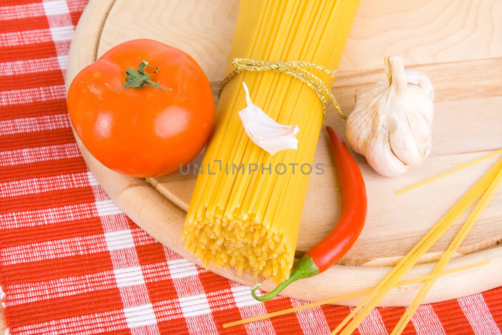 Golden raw dried Italian pasta with other ingredients on kitchen desk.